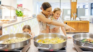 A buffet area with multiple food stations and a woman guiding a child. - Color Dolmen Family Village (Minervino di Lecce)