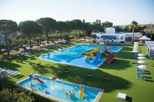 Una piscina al aire libre, sombrillas, sillones reclinables de piscina