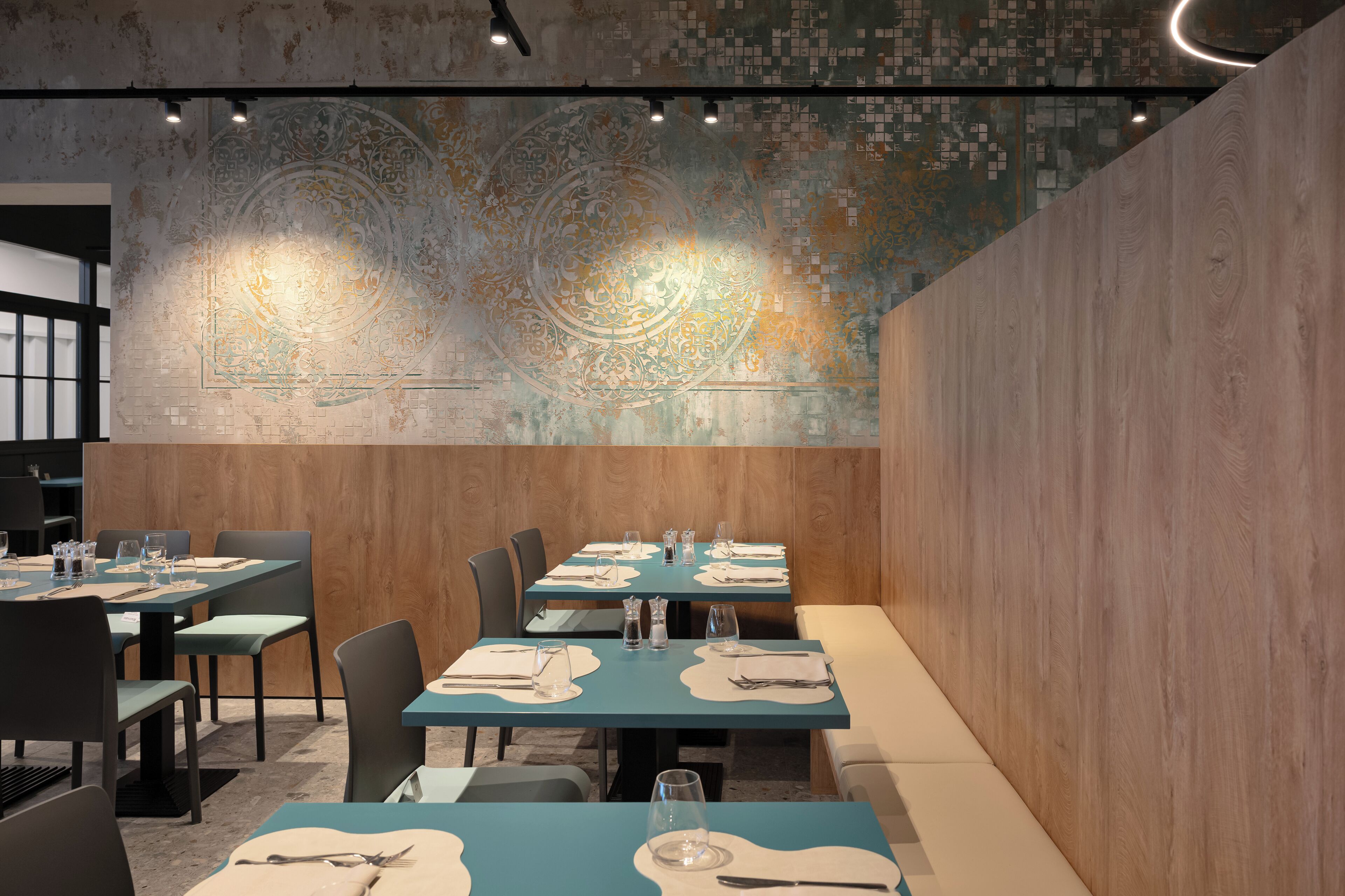 A restaurant with tables set for dining, a decorative wall mural, and a wooden accent wall.