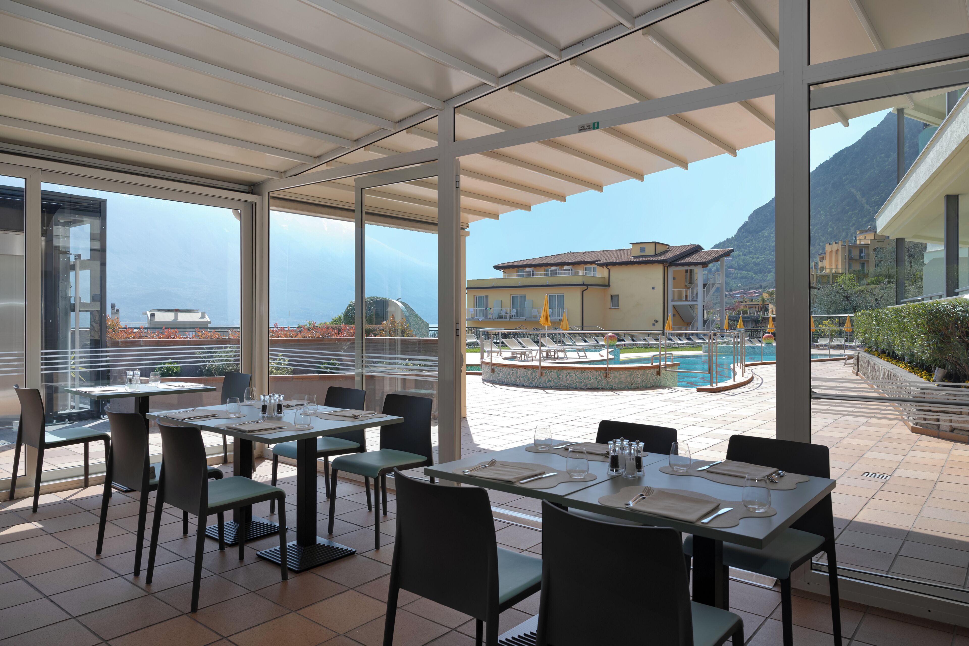 A rooftop restaurant with outdoor seating, a swimming pool, and mountain views.