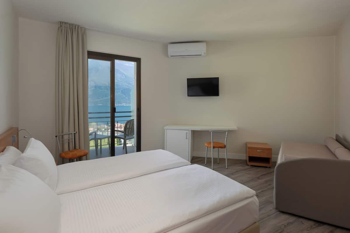 Une chambre d’hôtel équipée d’un lit, d’un bureau, d’une chaise, d’une télévision et offrant une vue sur l’extérieur.