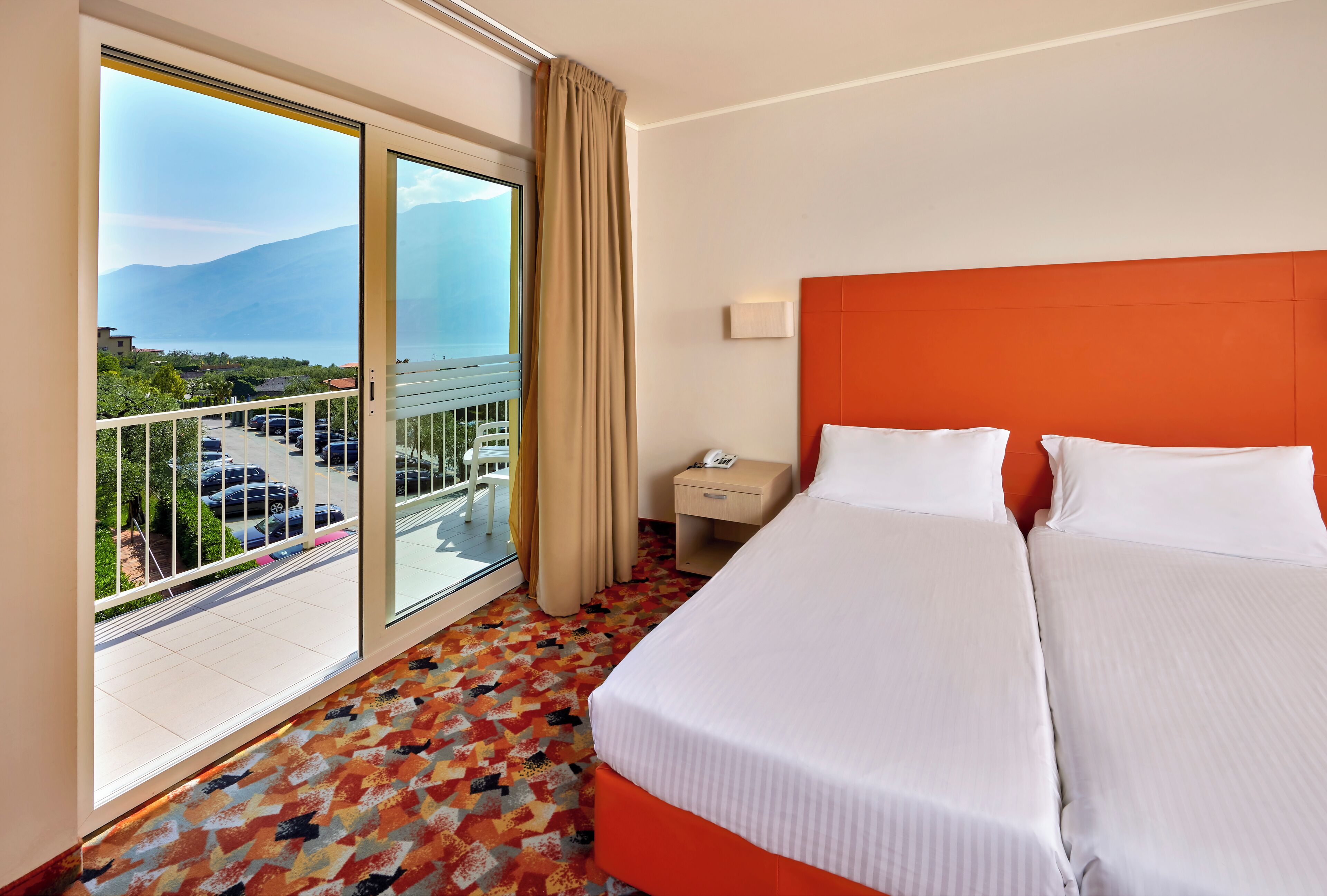 Ein Hotelzimmer mit großem Fenster, Balkon und einem Bett mit weißen Leinen.