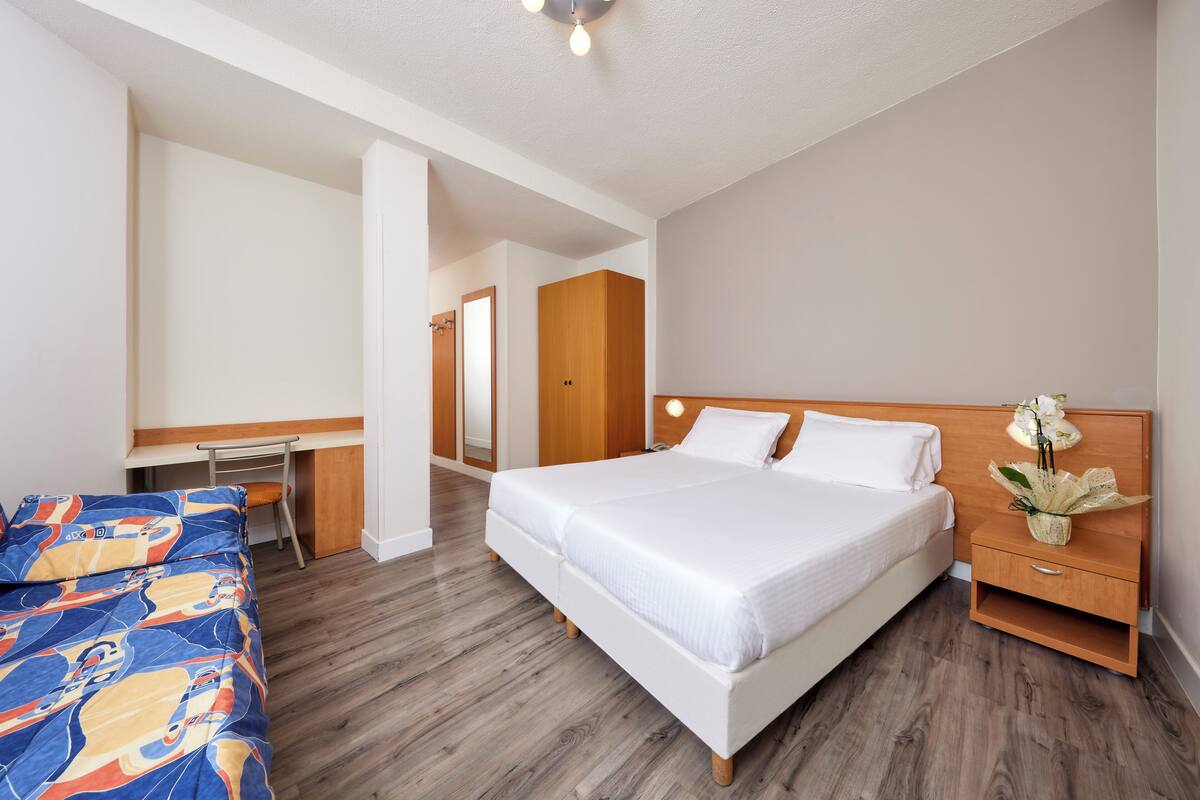 Une chambre à coucher avec un lit, un bureau et une table de chevet.