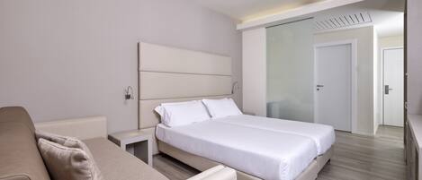 Una habitación de hotel moderna con una cama grande, un sofá y un vestidor.