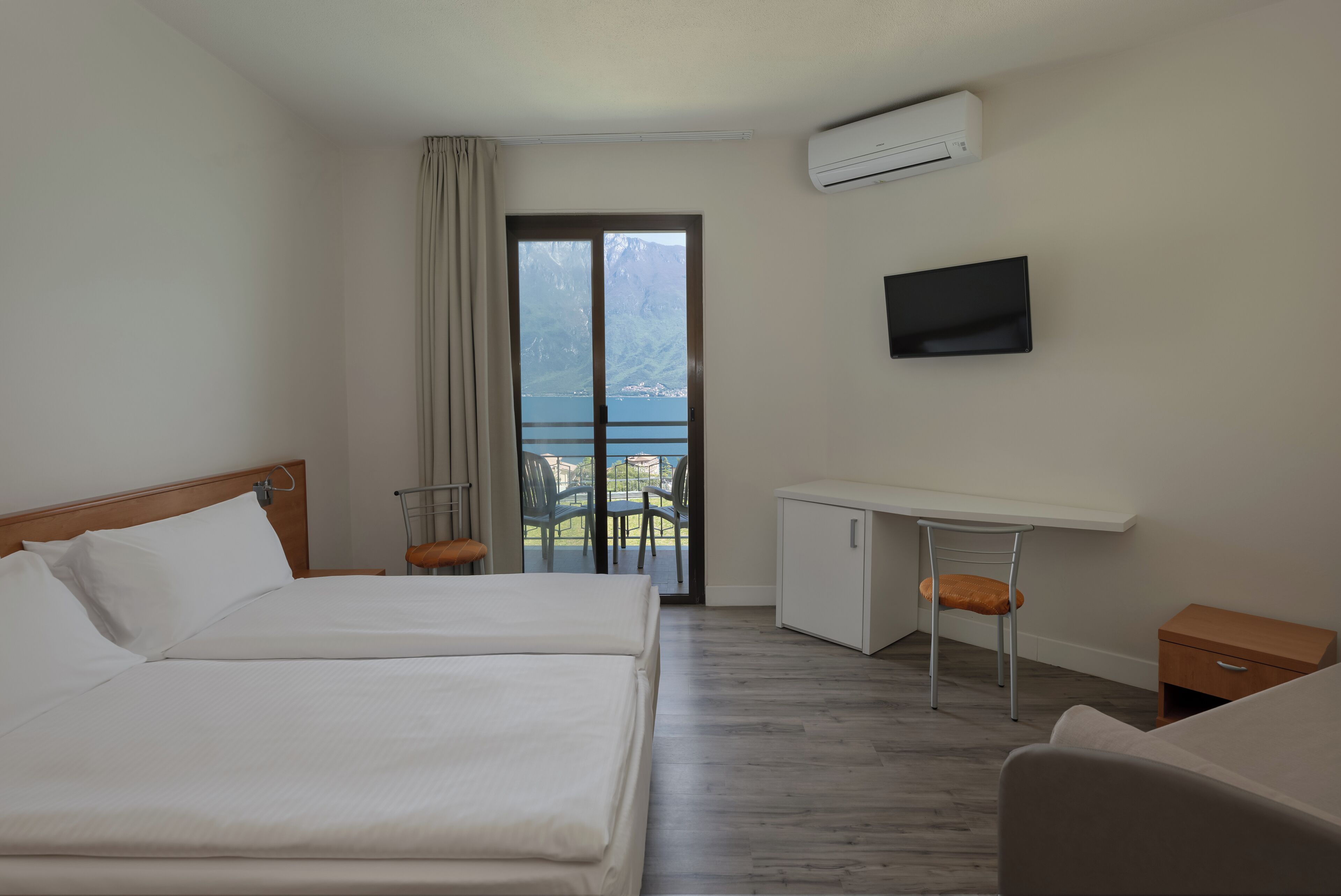 Ein Hotelzimmer mit Bett, Schreibtisch, Sessel, Fernseher und Blick auf die Berge.