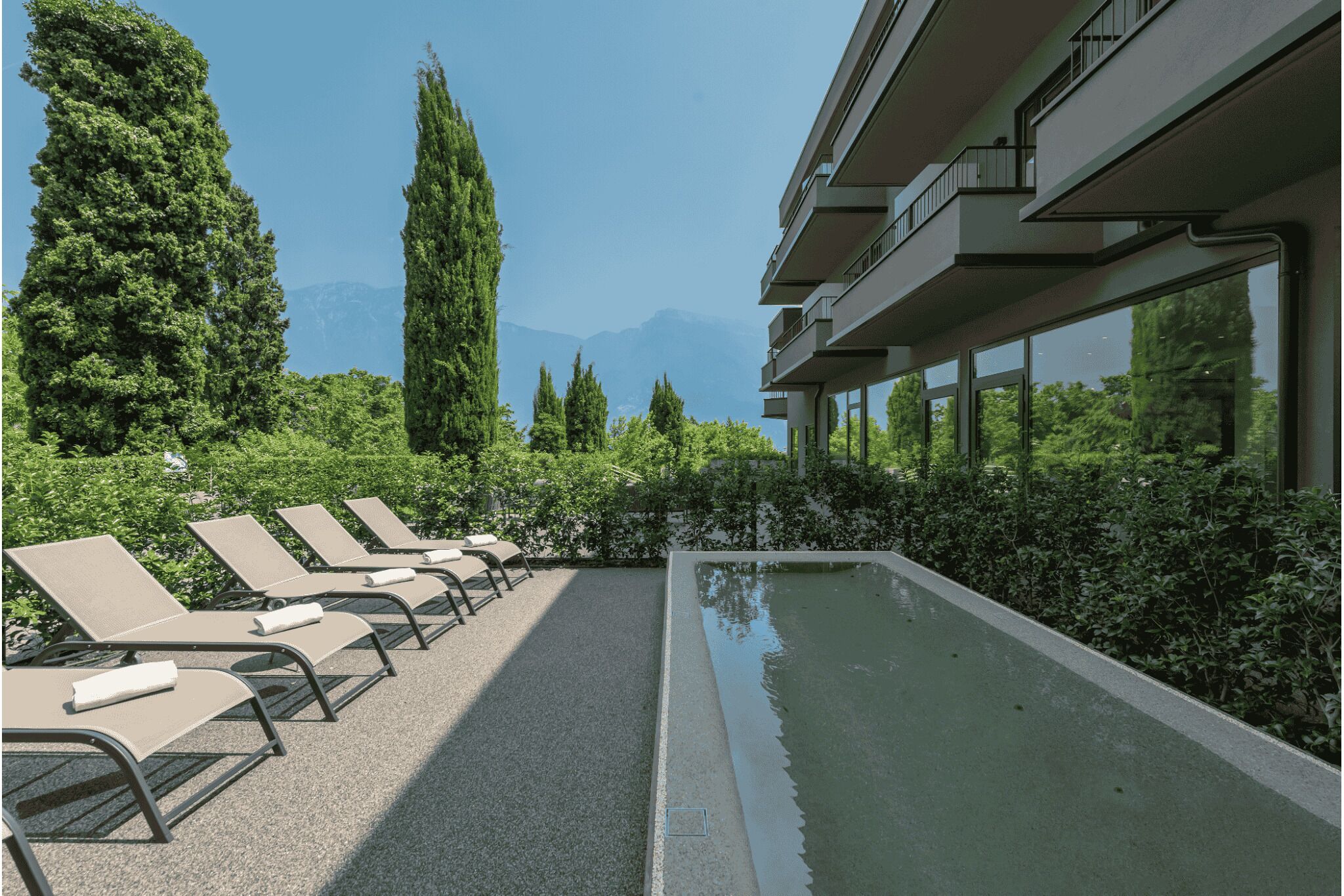 Area piscina con lettini, una piscina e un edificio con balconi.