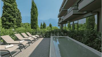 Area piscina con lettini, una piscina e un edificio con balconi.