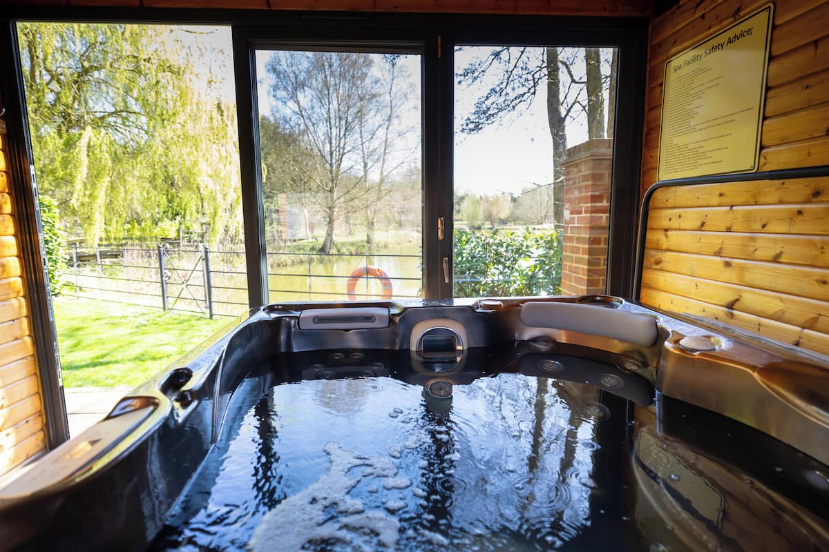 A hot tub with a view of a garden and a brick wall.