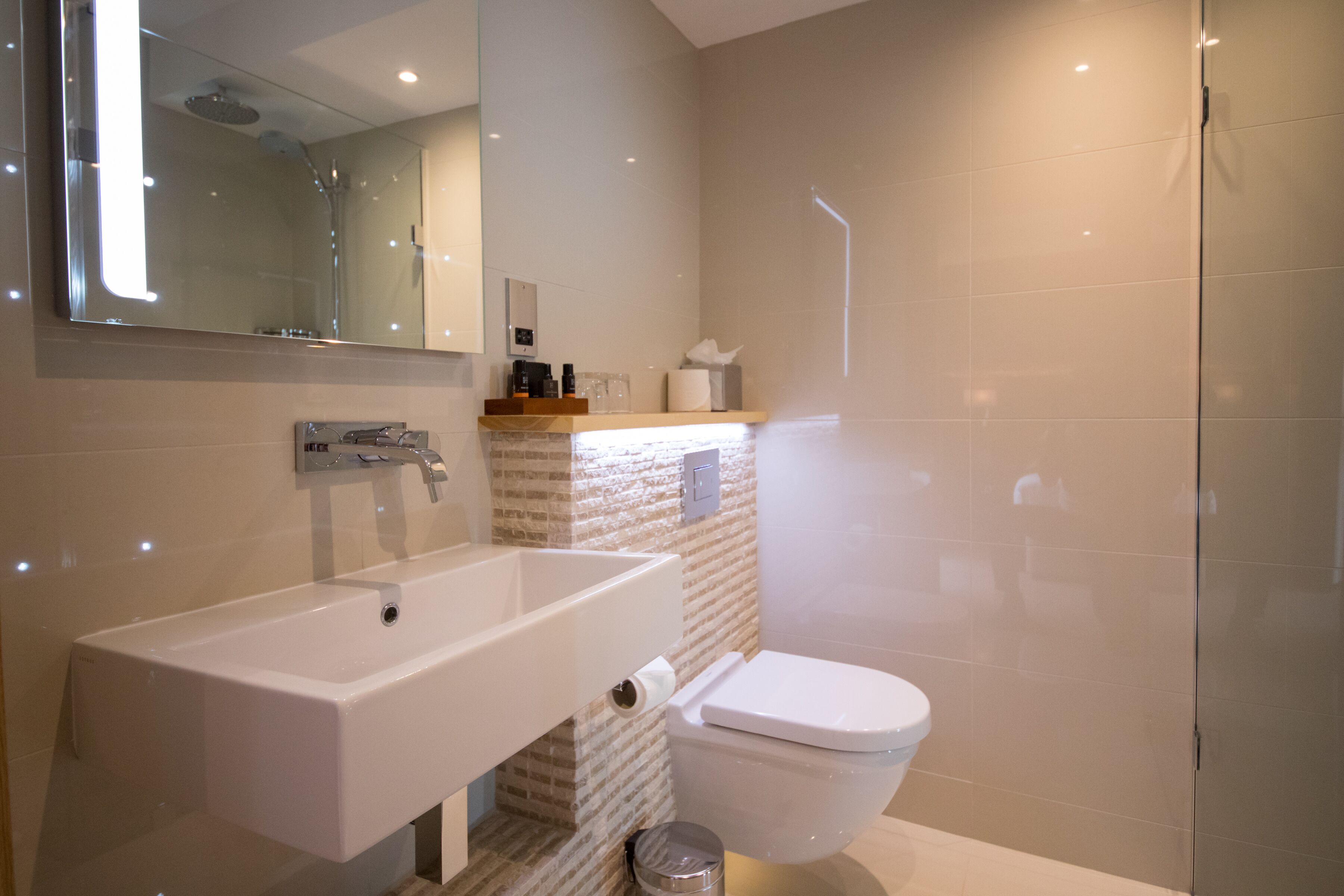 Een moderne badkamer met een groot wastafel, toilet en douche.