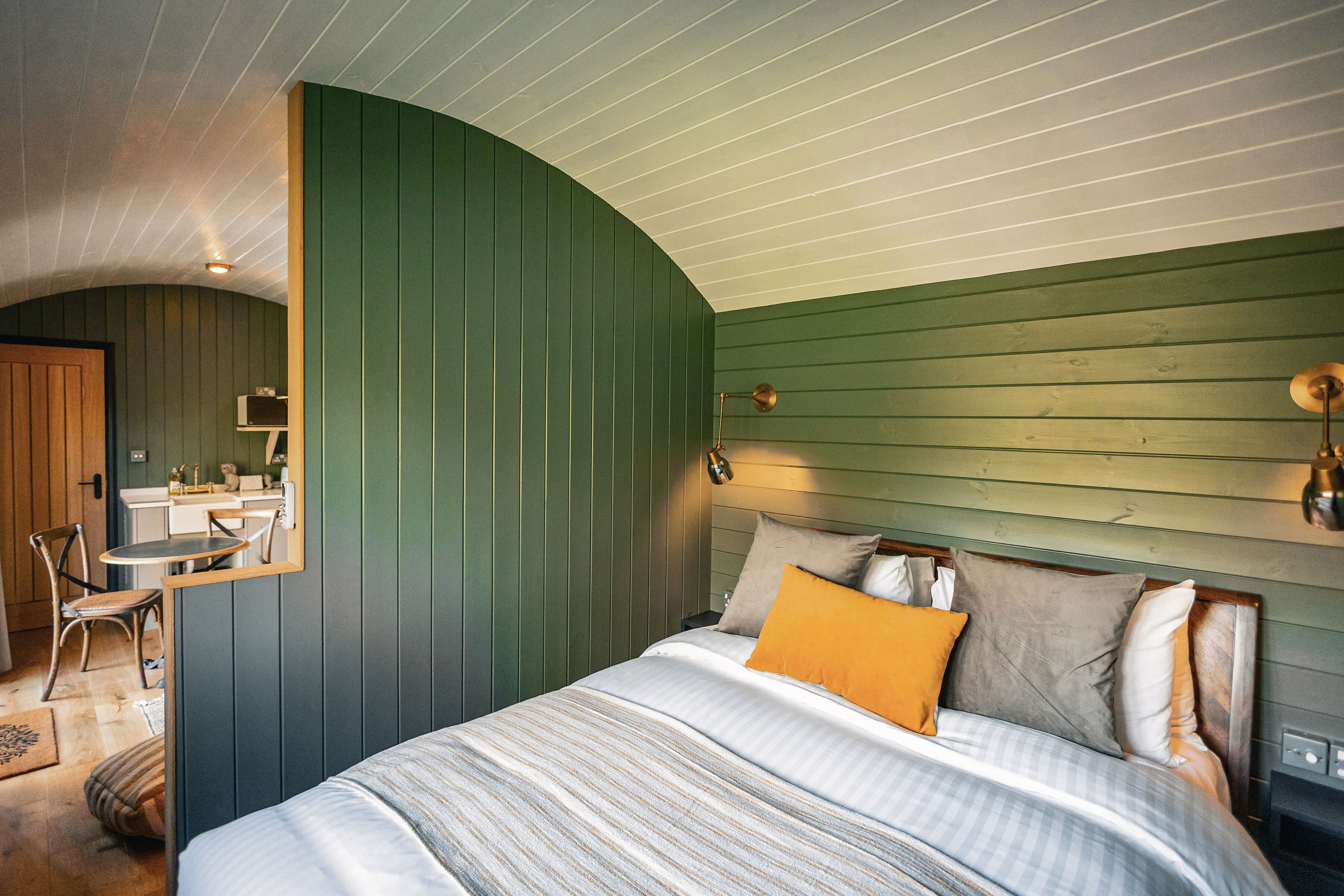 A bedroom with a curved ceiling, a bed with striped bedding, and a green wall.