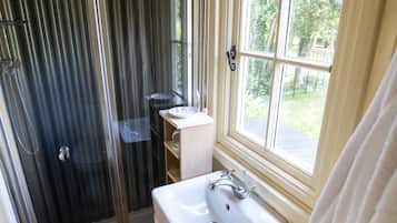 A bathroom with a shower, sink, and window.