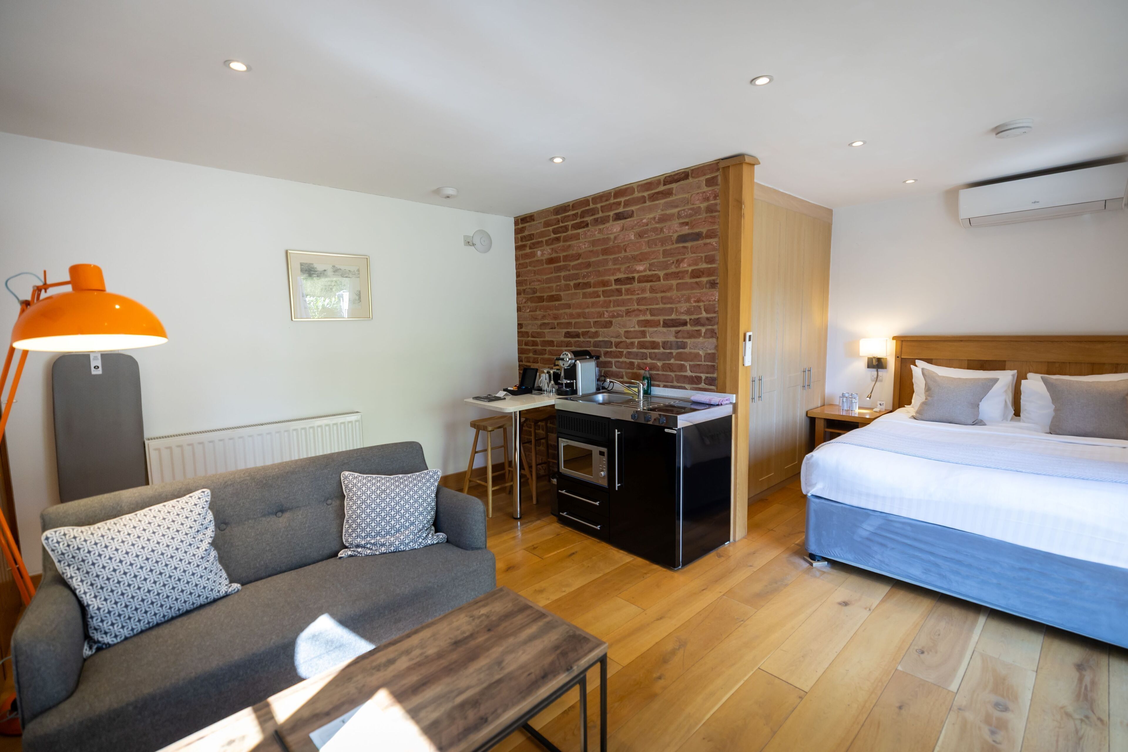 Une chambre d’hôtel compacte comprenant un coin cuisine, un lit, un canapé et un bureau.