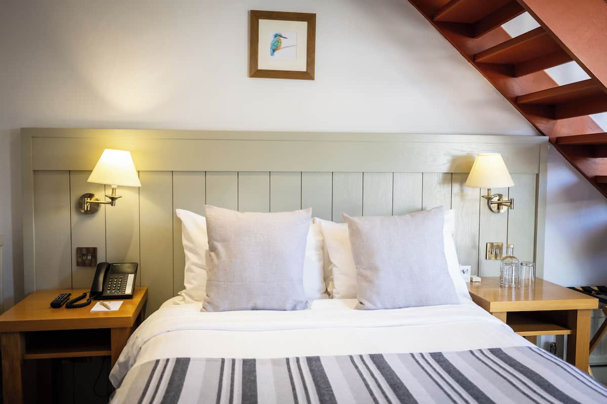 A hotel room with a bed, two bedside tables, lamps, a telephone, and a framed picture on the wall.