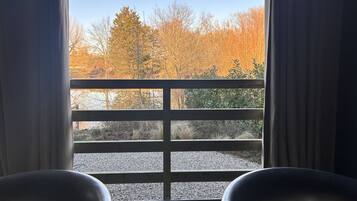A room with a large window, wooden railing, and two chairs.