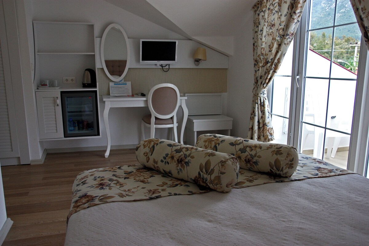 Ein Schlafzimmer mit einem Bett, einem Schreibtisch mit Computer, einem Stuhl und einem kleinen Kühlschrank.