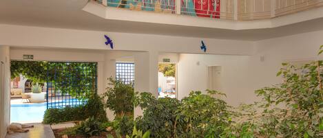 A hotel lobby with a pool, indoor plants, and a staircase with a decorative railing.