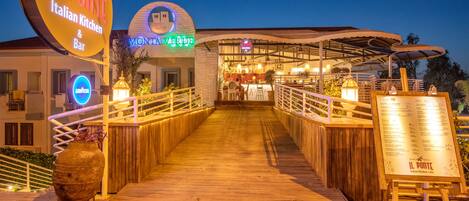 Un paseo marítimo de madera que conduce a un restaurante con un letrero que dice "IL PONTE Italian Kitchen & Bar".