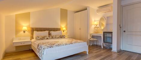A bedroom with a bed, bedside lamps, a desk with a chair, a mirror, and a wardrobe.
