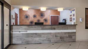 A reception area with a stone counter, three ceiling lights, and a wall with circular patterns.