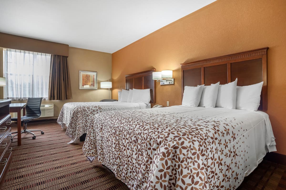 A hotel room with two beds, a desk, and a chair.