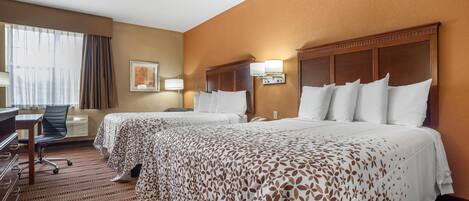 A hotel room with two beds, a desk, and a chair.