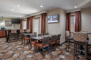 A conference room with a large table, chairs, a TV screen, and a patterned carpet.