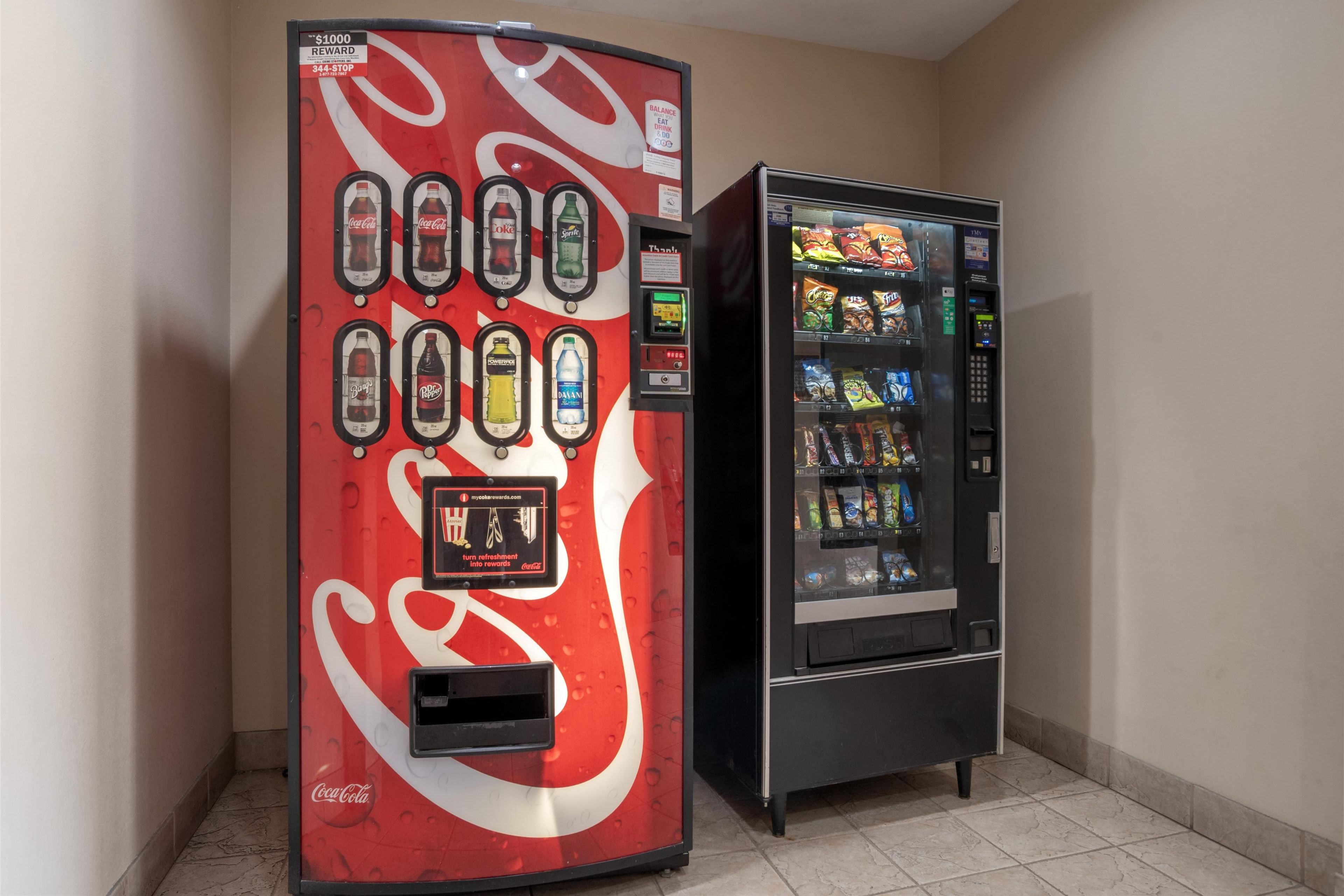A Coca-Cola branded vending machine with a reward program and a snack vending machine next to it.