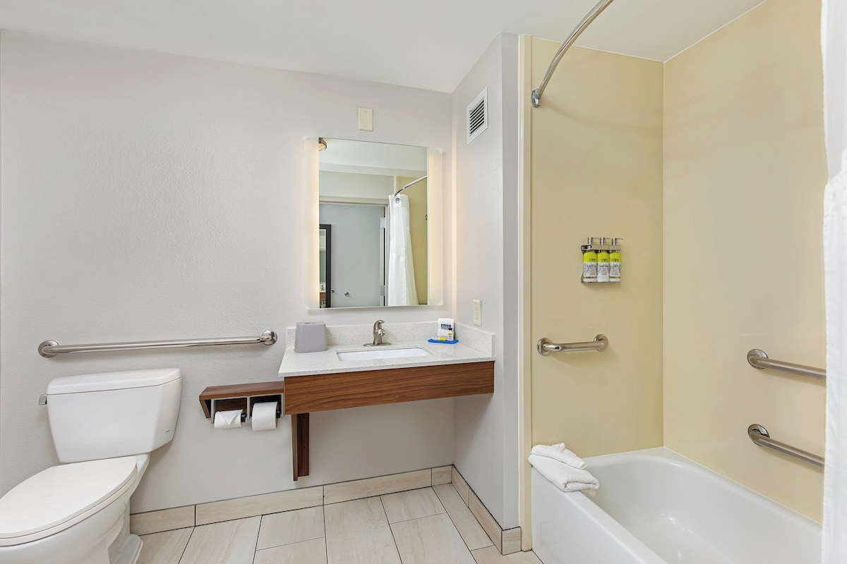 A modern bathroom with a toilet, sink, mirror, and shower.