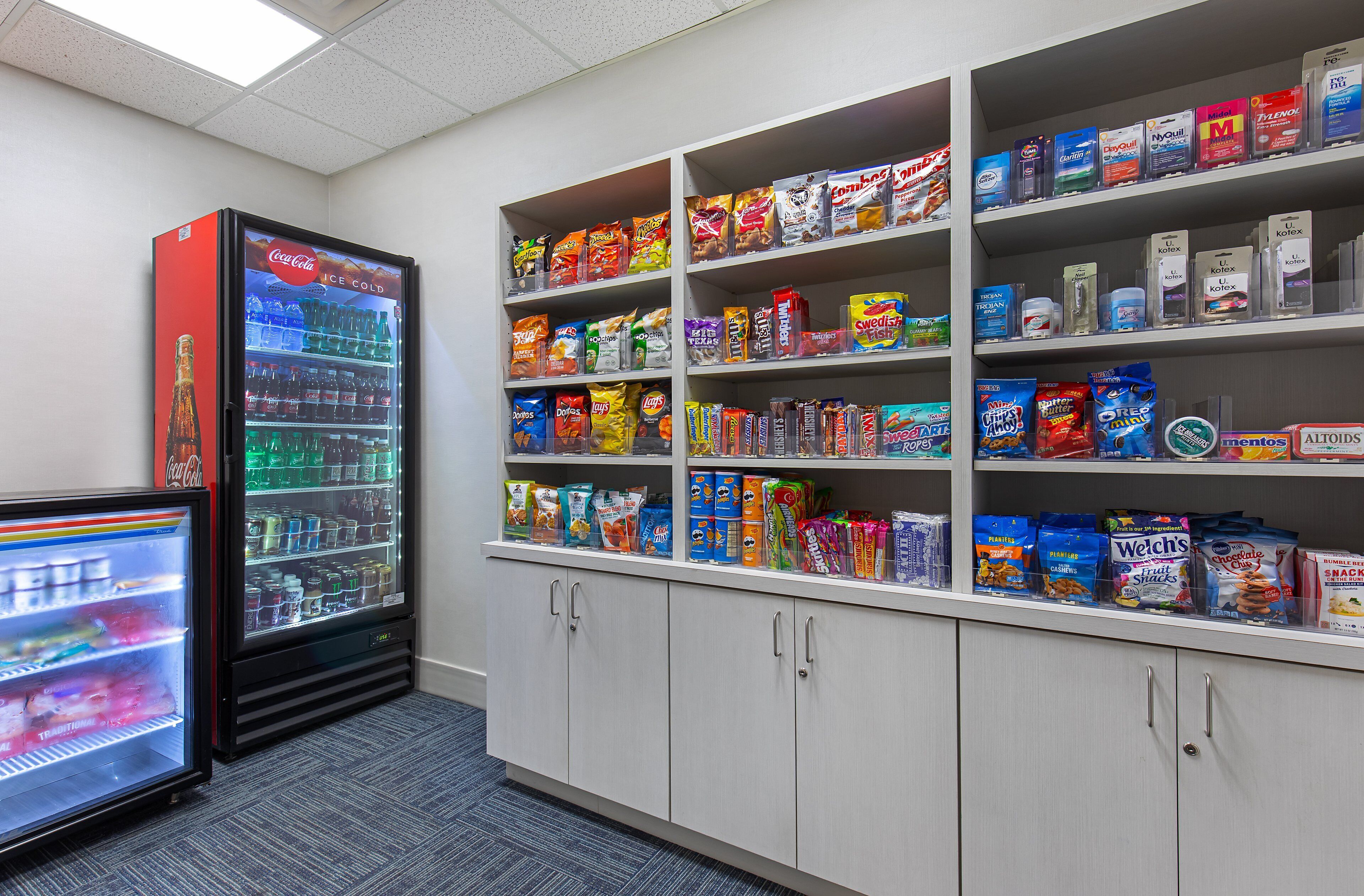 A vending area with a Coca-Cola refrigerator and a variety of snack and drink options.