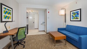 A hotel room with a desk, office chair, blue sofa, and two framed artworks on the walls. - Holiday Inn Express Mt. Juliet by IHG (Mount Juliet)