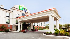 Un hotel con entrada techada, fachada de ladrillo y un letrero que dice 'Holiday Inn Express & Suites'.