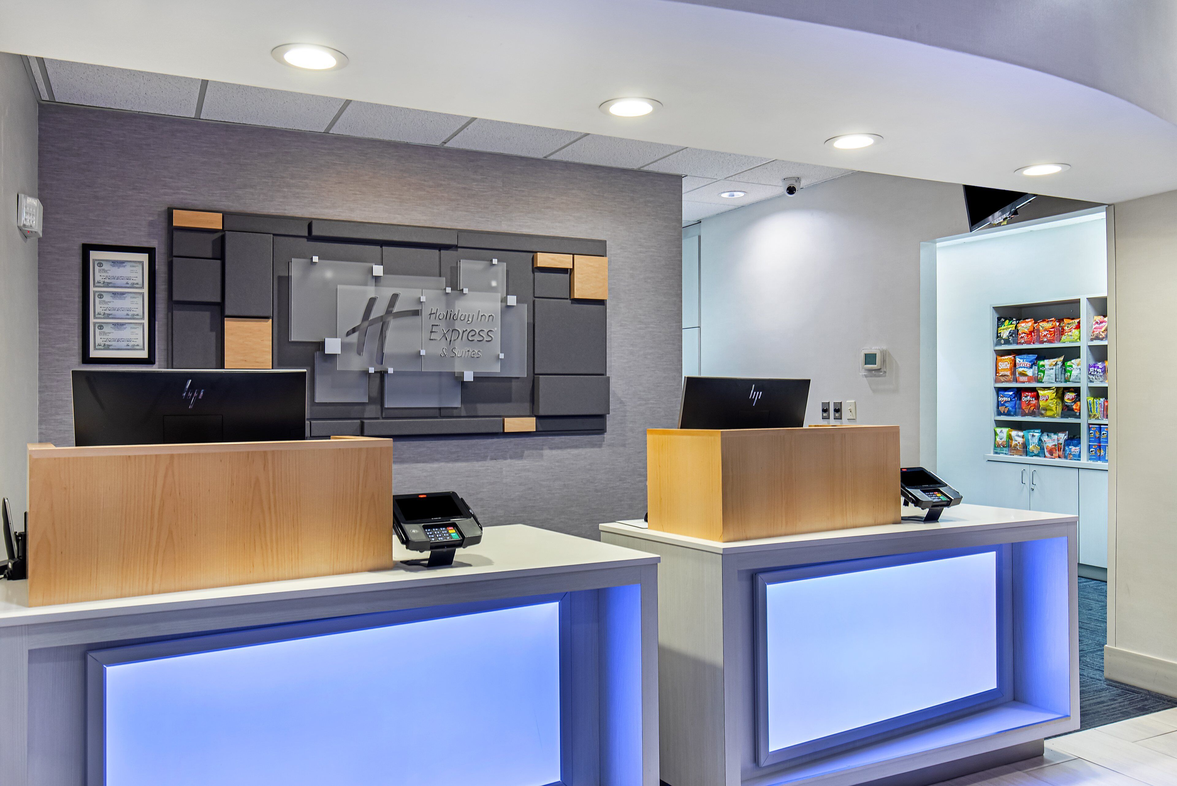 A hotel reception area with two reception desks, a wall-mounted sign, and a snack vending machine.