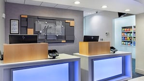 A hotel reception area with two reception desks, a wall-mounted sign, and a snack vending machine. - Holiday Inn Express Mt. Juliet by IHG (Mount Juliet)
