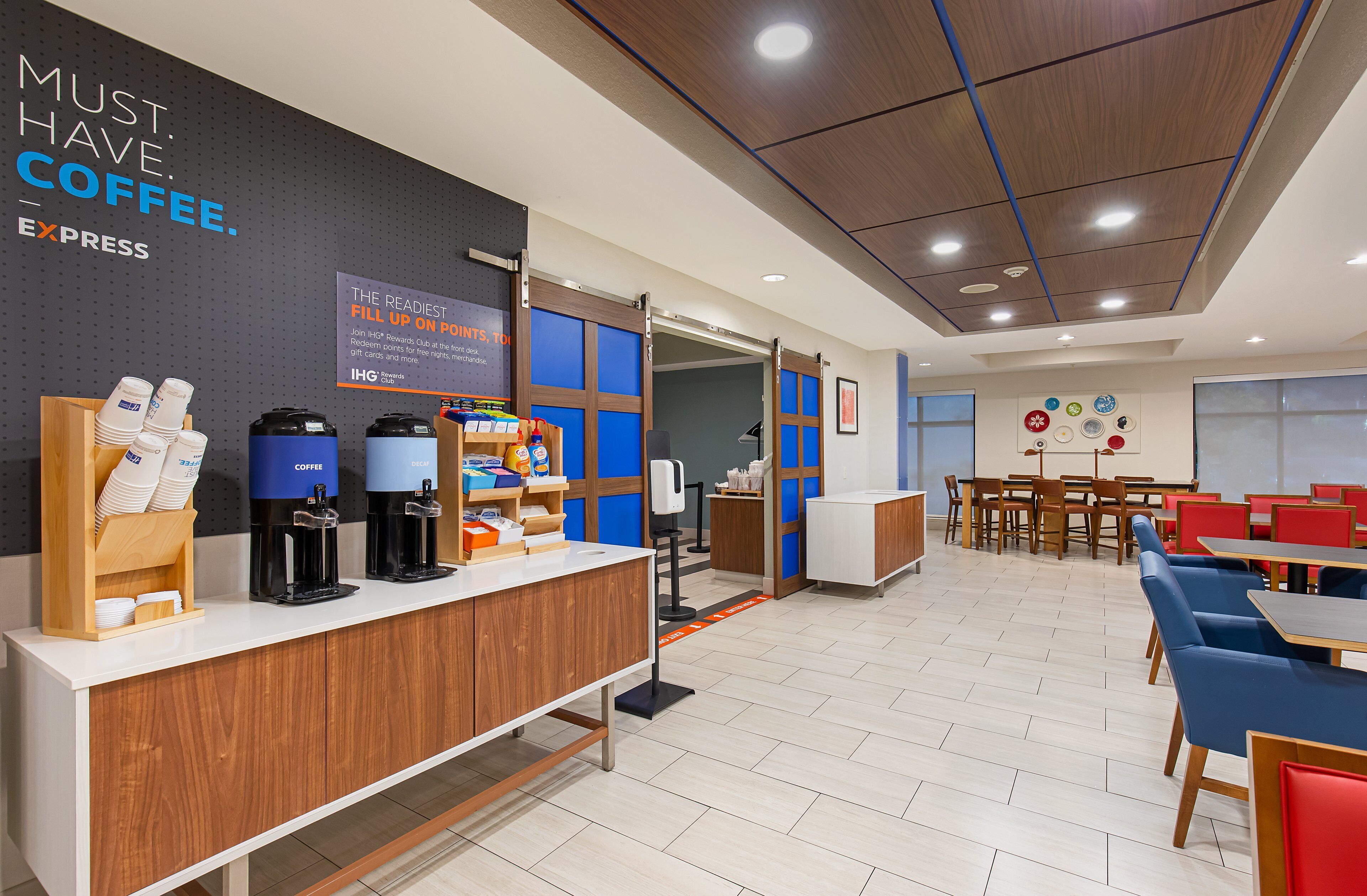 A modern coffee station with multiple coffee machines and a sign promoting a rewards program.