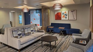Un salon moderne comprenant un canapé, des fauteuils, une table basse et un mur d’accent bleu orné d’une carte.