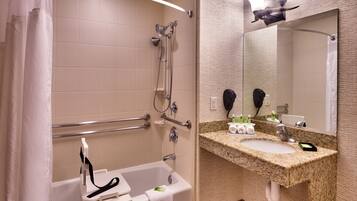 A modern bathroom with a bathtub, shower, vanity with a sink, and a large mirror.