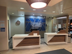 A hotel reception area with a modern design, including a reception desk, a clock, and a sign indicating the hotel's name. - Holiday Inn Express & Suites Kanab by IHG (Kanab)
