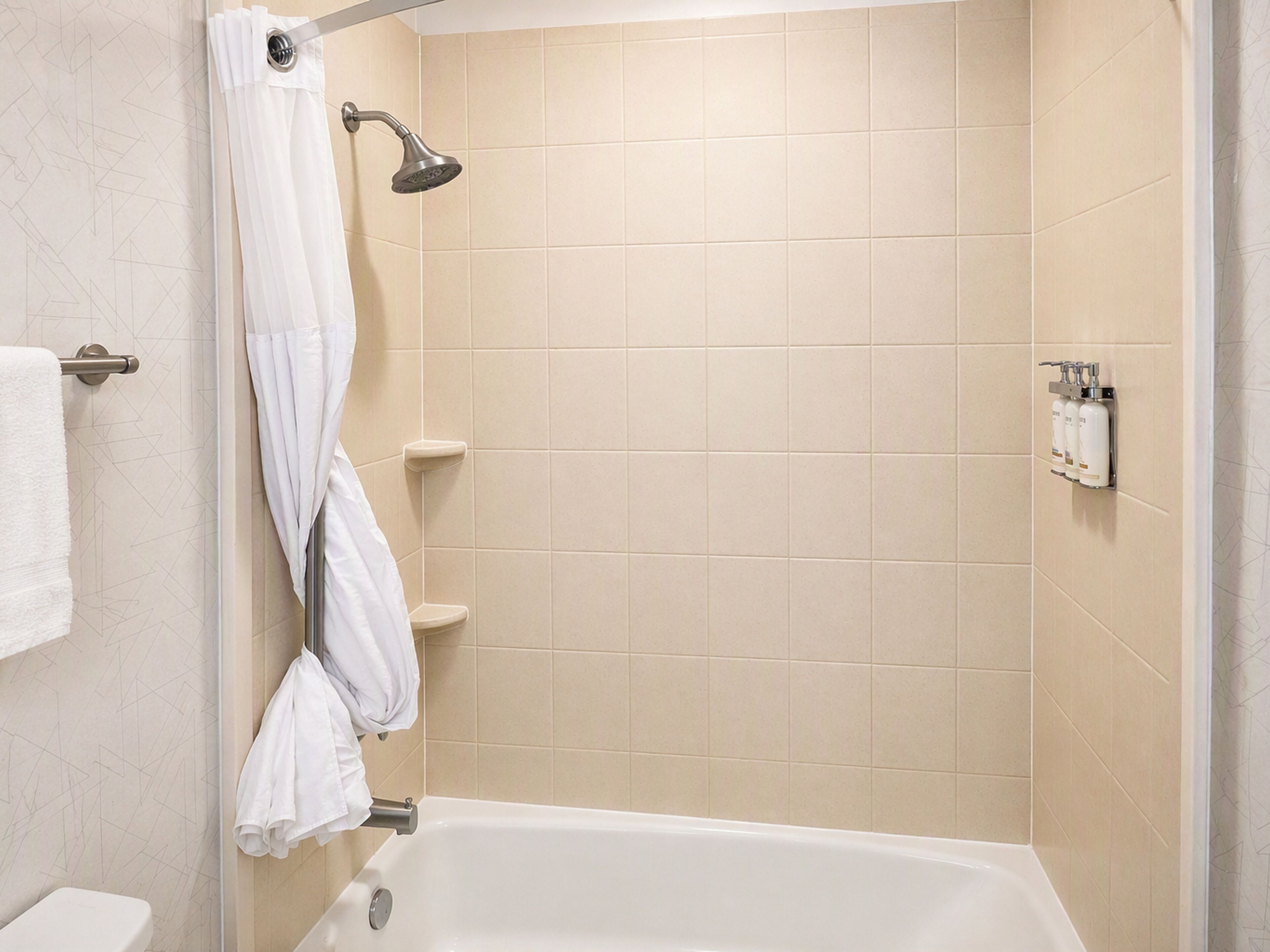 A bathroom with a bathtub, a showerhead, and a towel rack.
