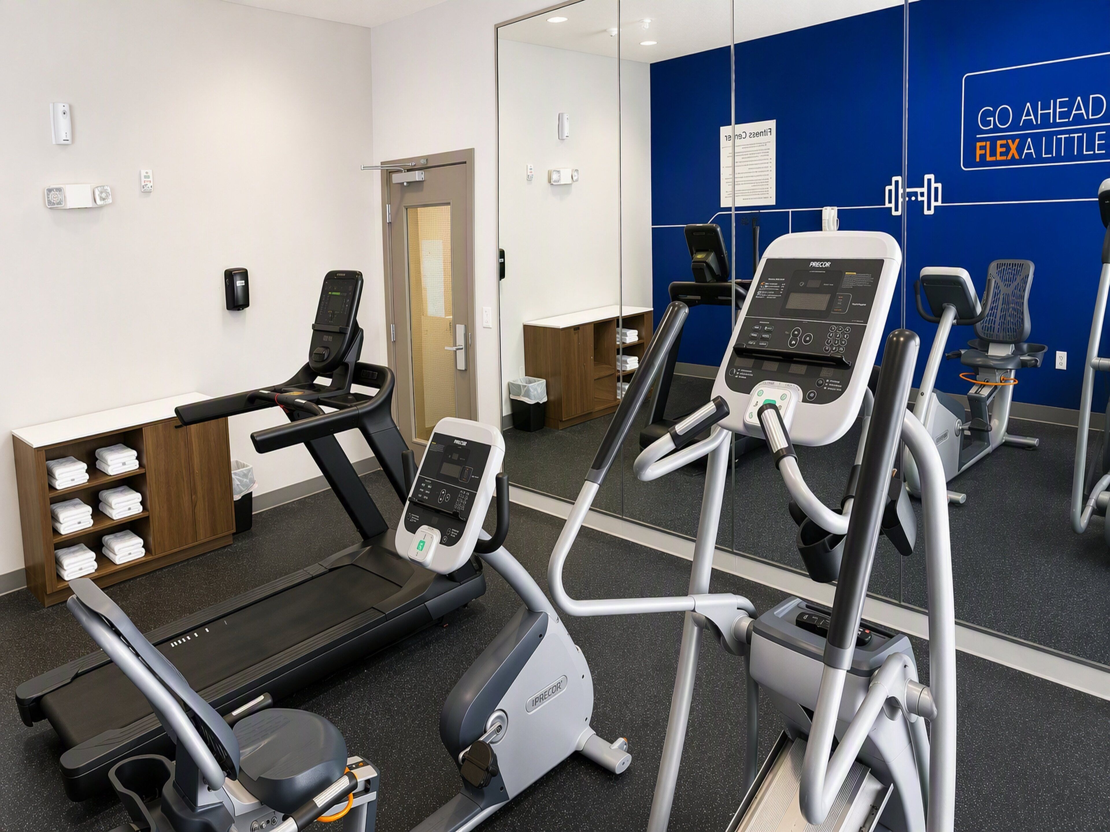 A fitness center with treadmills, ellipticals, and a mirrored wall with motivational text.