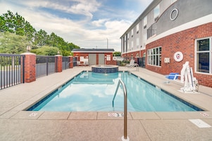 Piscina com placa indicando proibição de mergulho, posto de salva-vidas e um edifício de tijolos ao fundo.