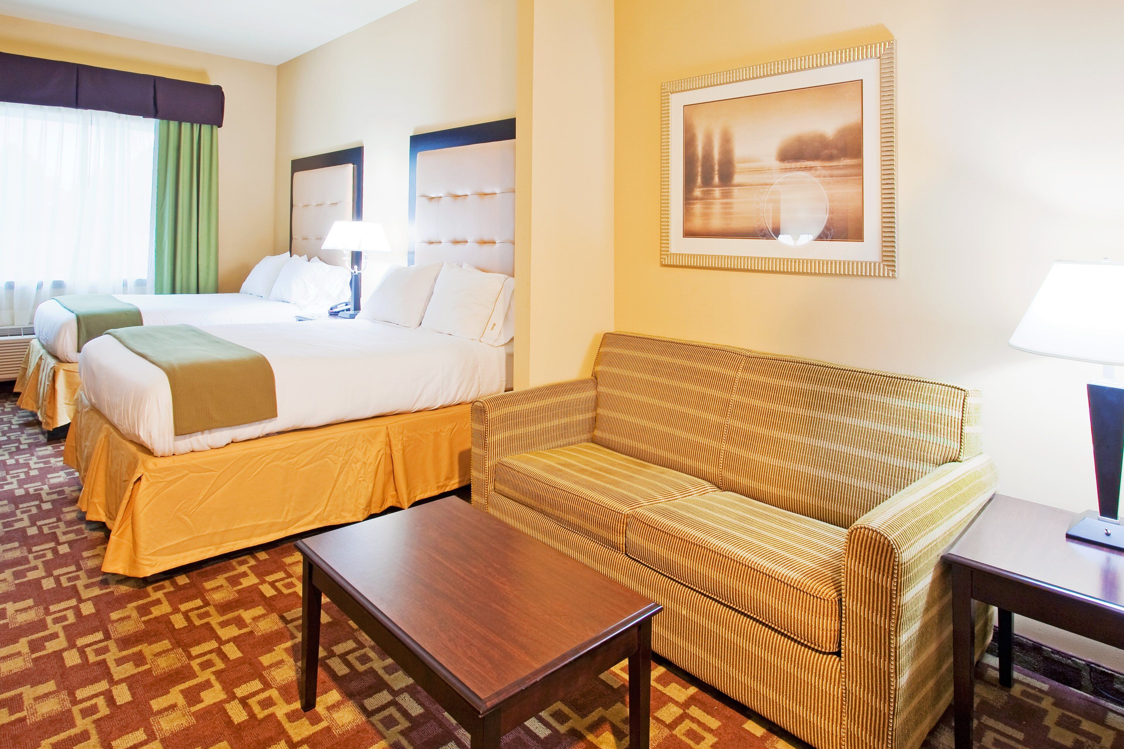 A hotel room with a bed, a sofa, a table, and a picture on the wall.
