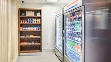 Un área de máquinas expendedoras con opciones de comida y bebida, que incluye diversos snacks y bebidas embotelladas.