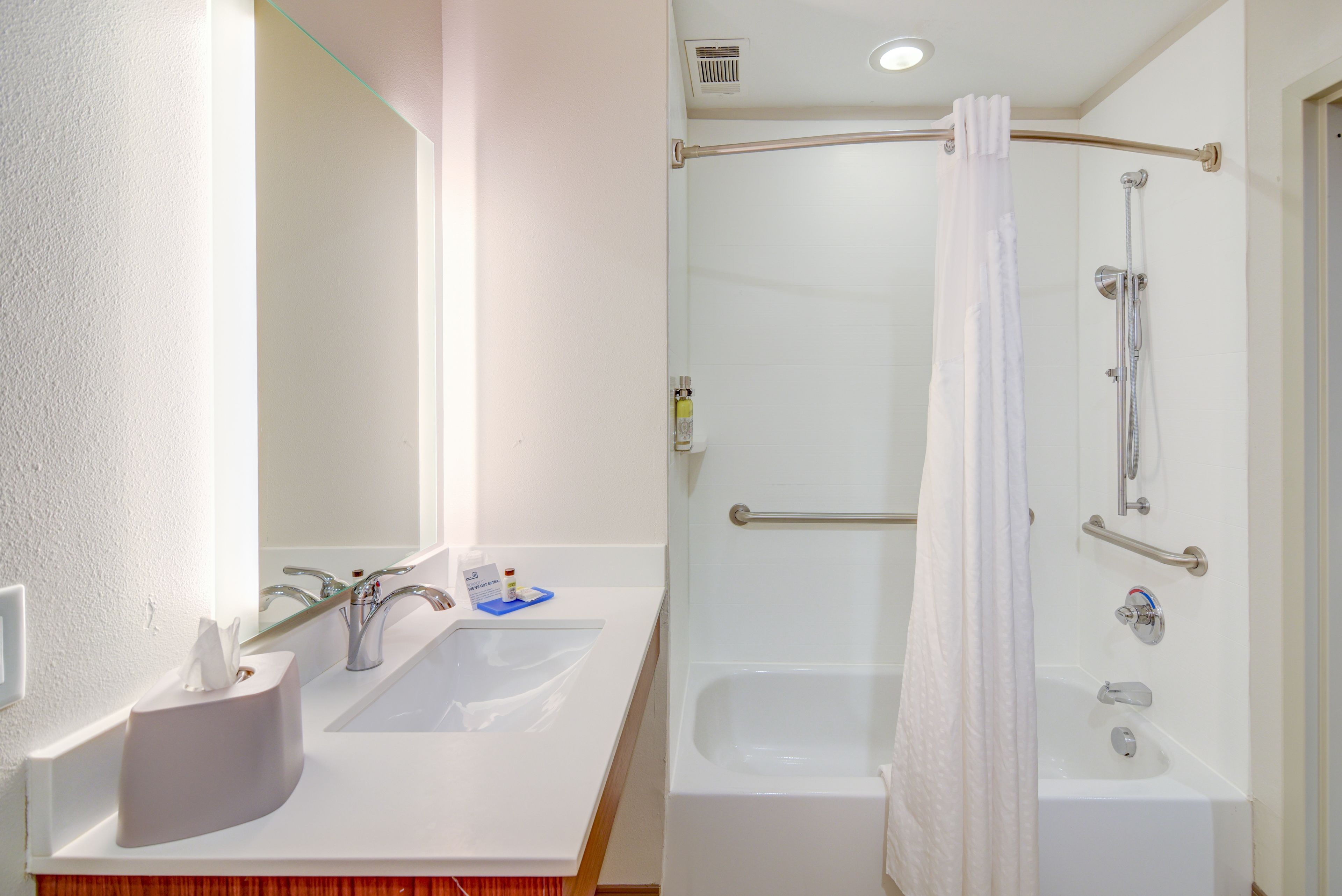 Un baño con lavamanos, espejo y ducha.