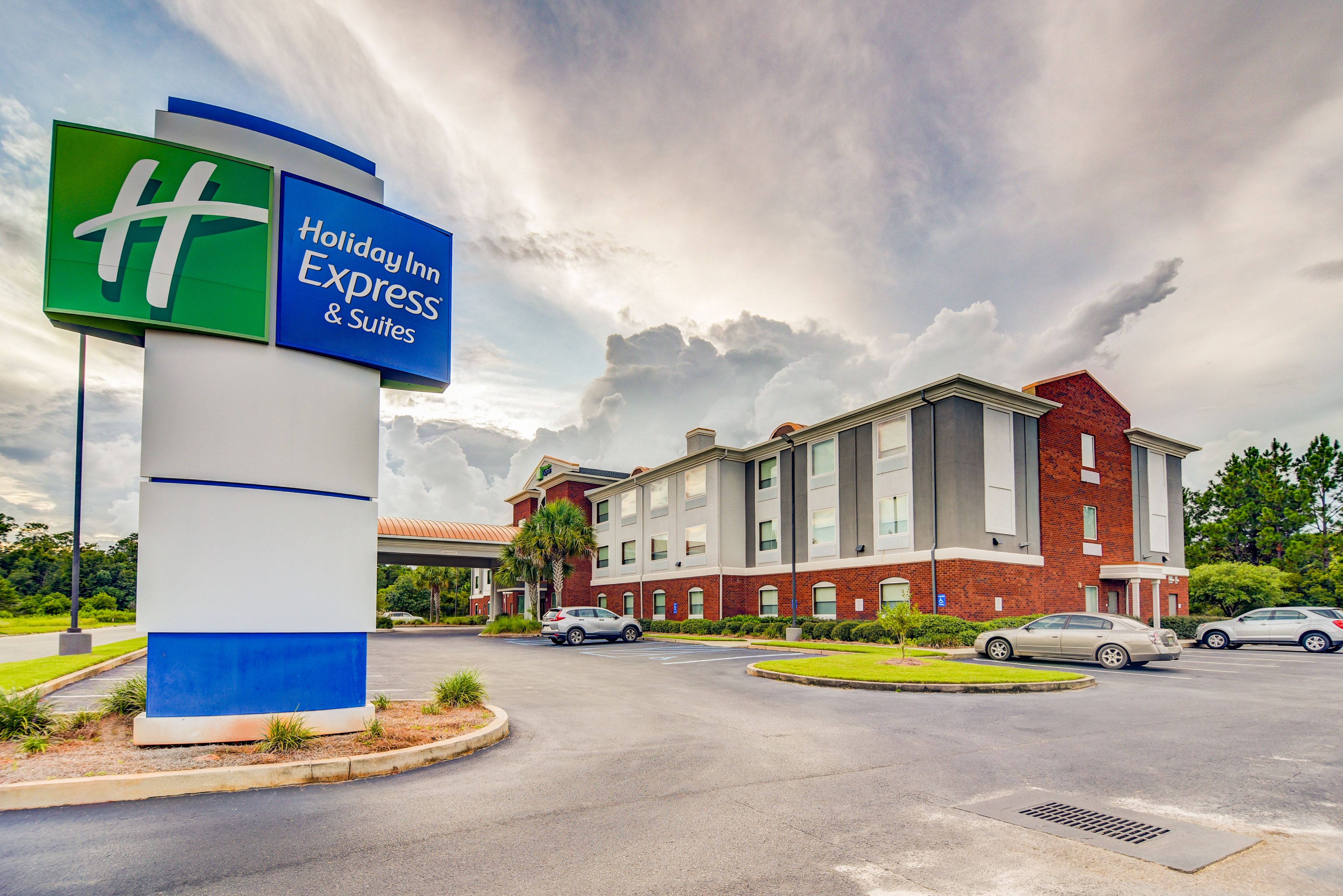 A Holiday Inn Express & Suites with a large sign, a parking lot, and a building with a brick facade.