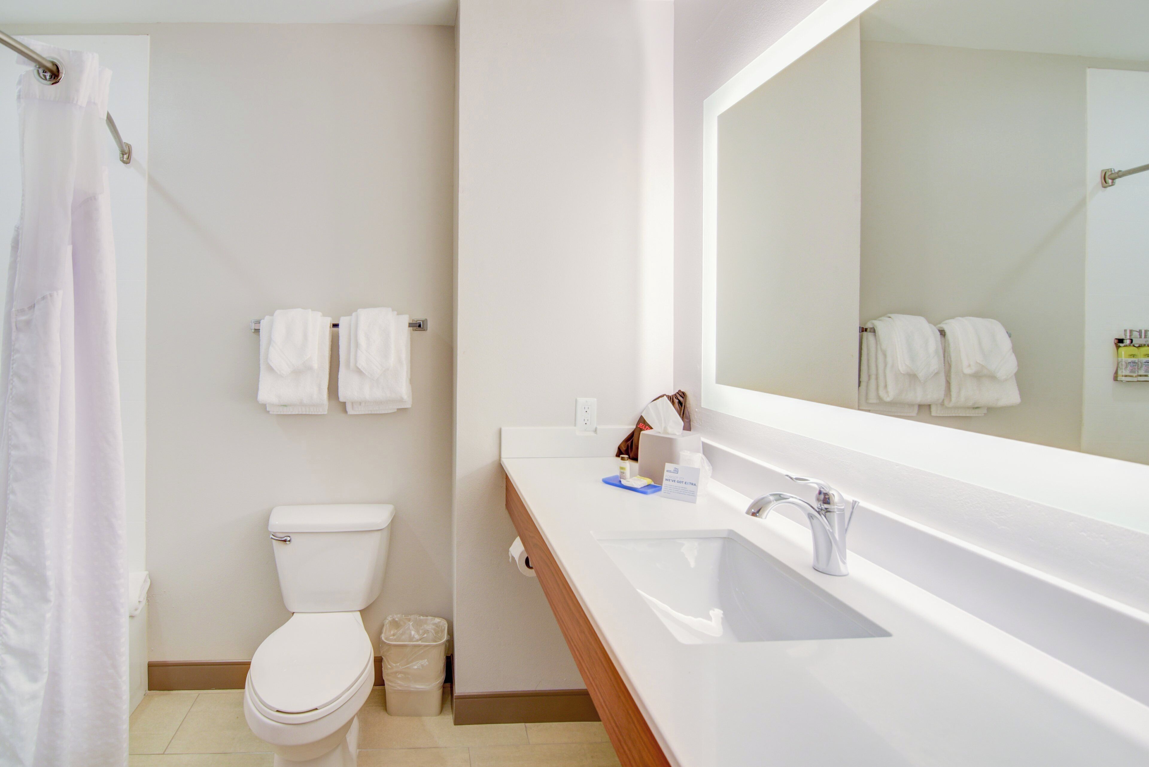 A bathroom with a toilet, a sink, a mirror, and a shower curtain.