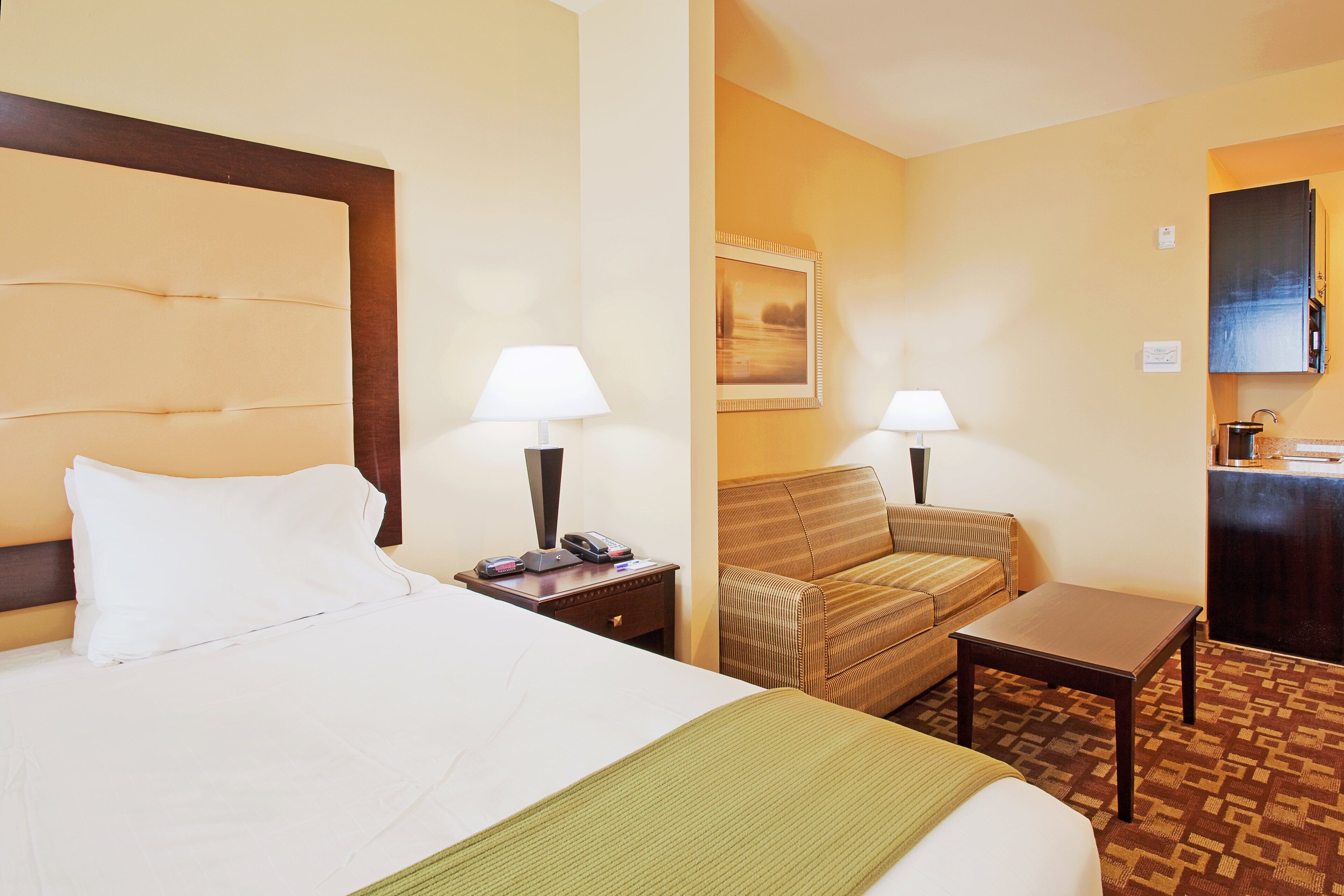 A hotel room with a bed, two bedside tables, a chair, a desk, and a small table.