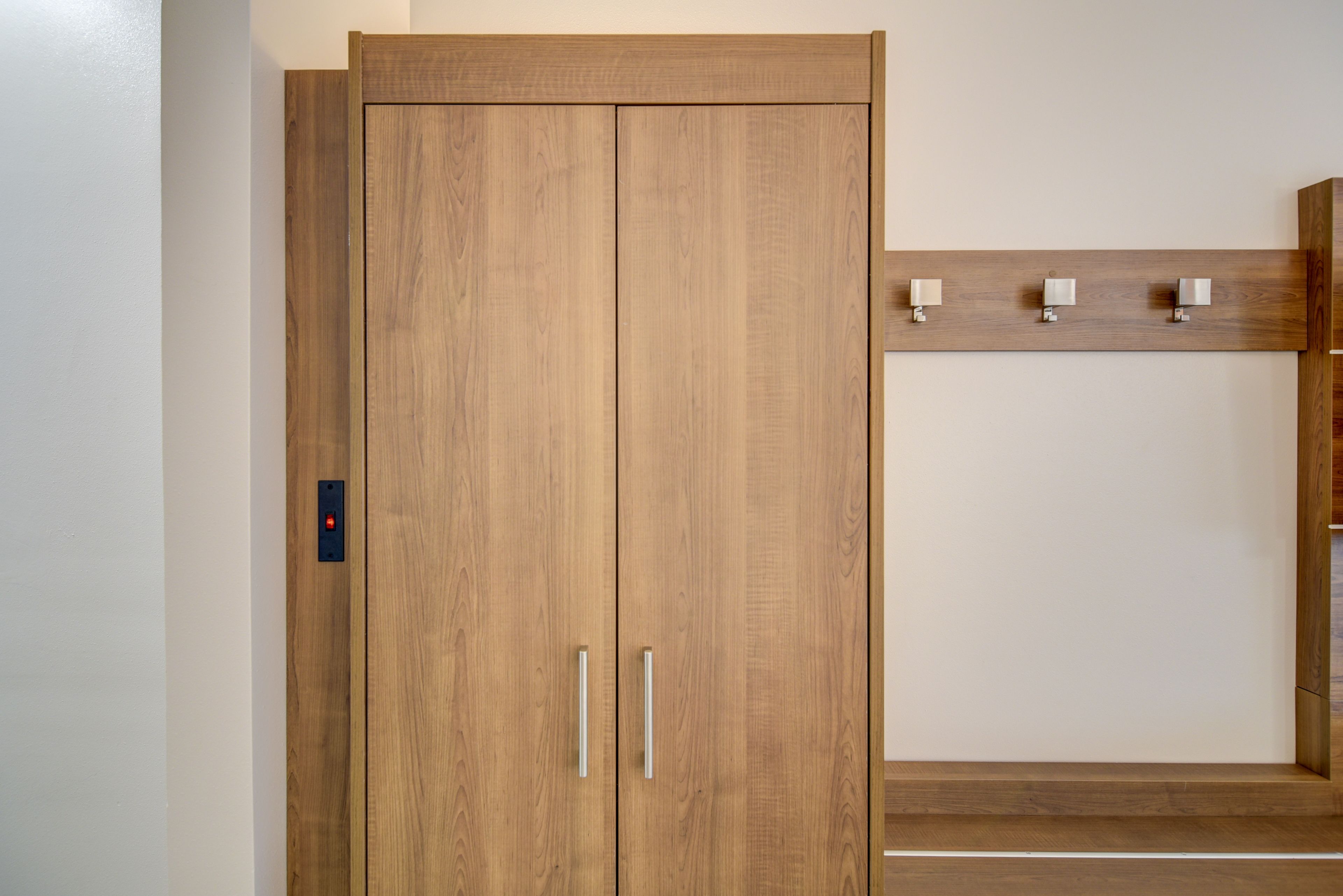 Un armario de madera con dos puertas y un estante superior.