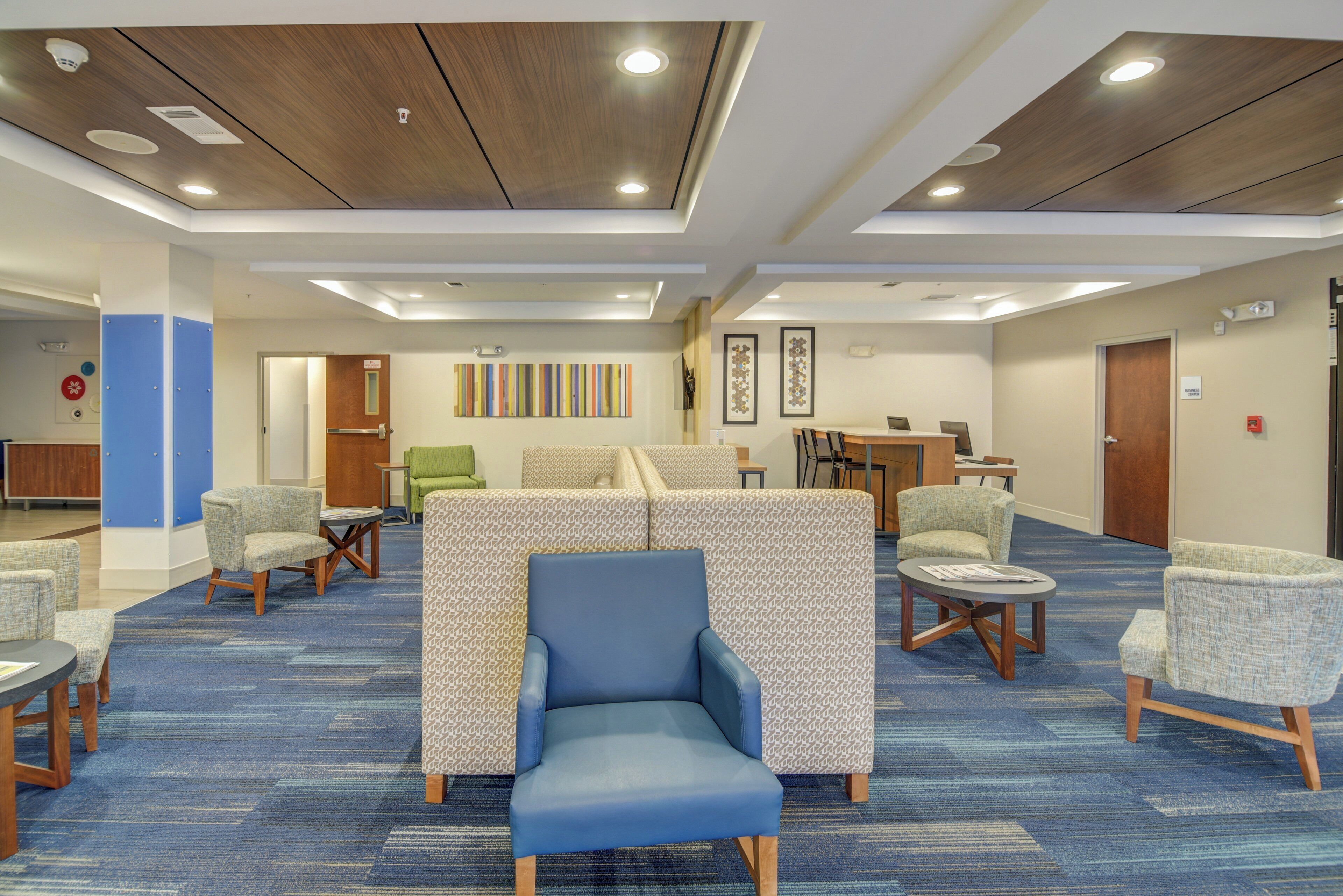 A hotel lobby with seating areas, a reception desk, and a business center.