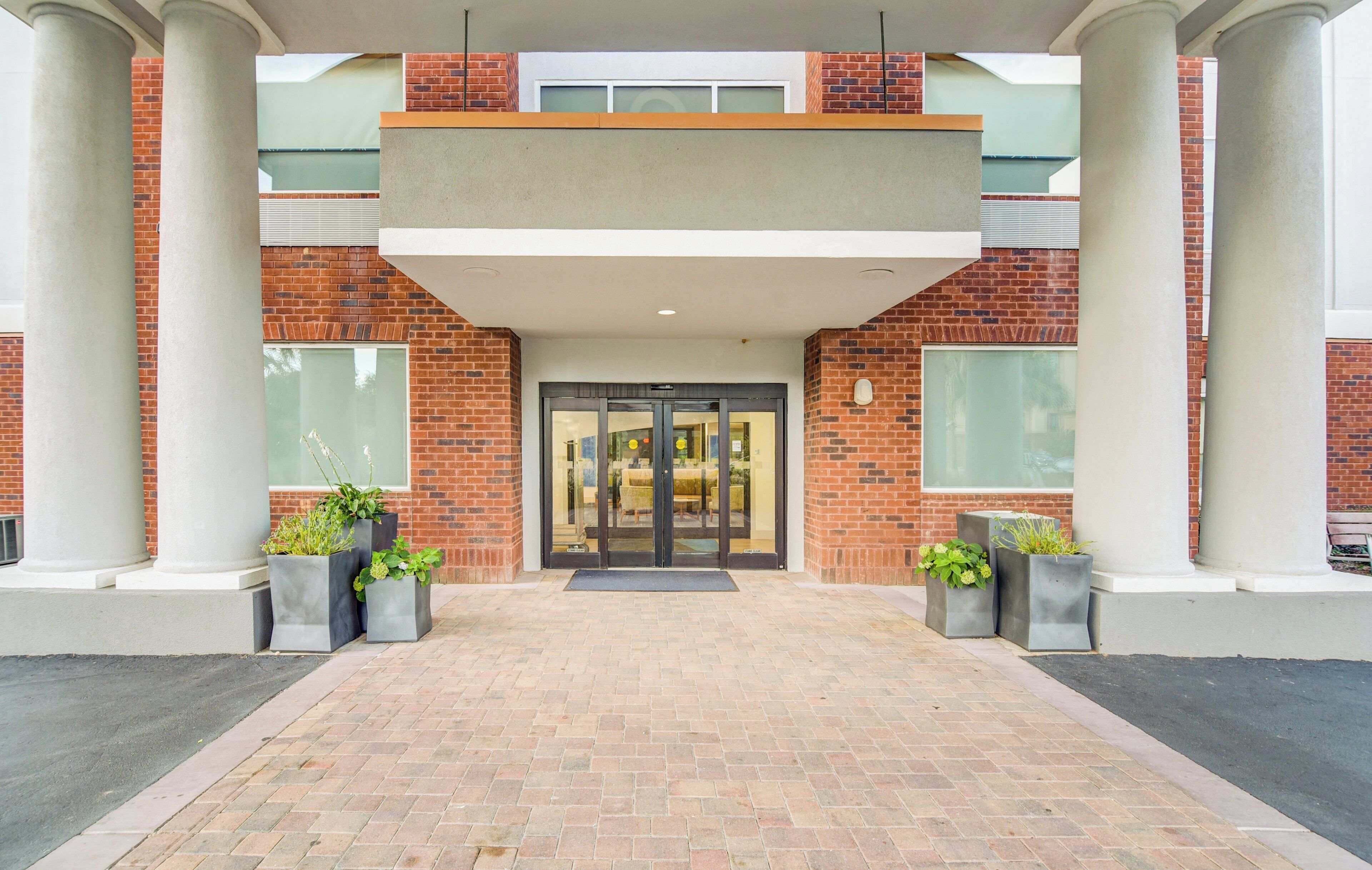 A building entrance with a brick facade, large columns, and a glass door.