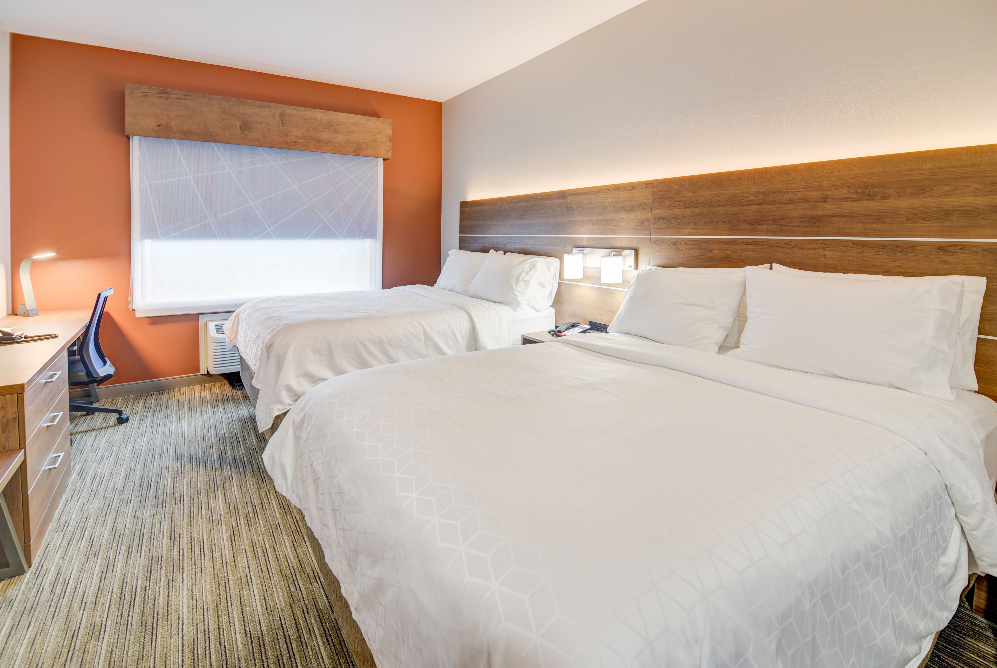 A hotel room with two beds, a desk, and a chair.